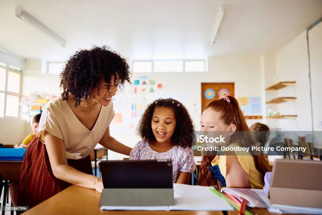 Junge Lehrerin erklärt Schülern Lerninhalte mit einem digitalen Tablet